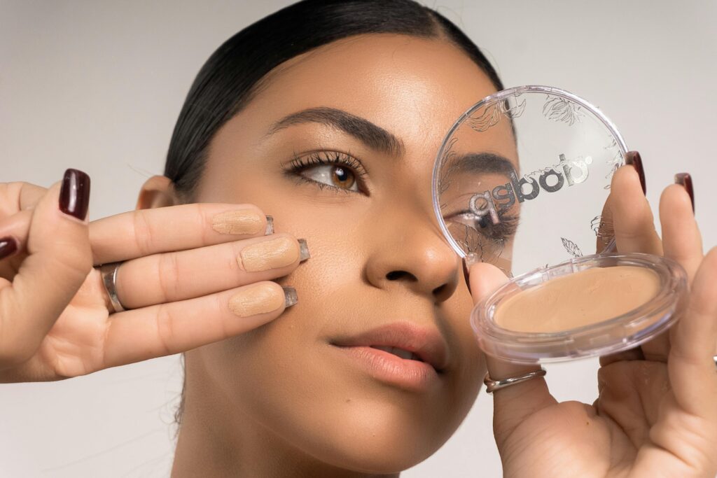 Detailed close-up of a woman applying makeup foundation using a compact.